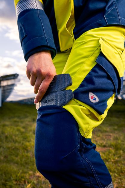 One person places a knee protector in the knee pad pocket of the work trousers.